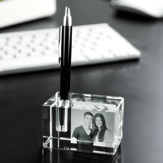 Der Engravy 2D-Stiftehalter mit Foto-Gravur ist ein eleganter Stiftehalter aus klarem Acryl für den Schreibtisch. Er ist mit einem schwarzen Stift und einem personalisierten Schwarzweißfoto eines lächelnden Paares auf einer dunklen Oberfläche mit einer weißen Tastatur versehen. Für eine zusätzliche persönliche Note können Sie ihn mit einer individuellen Gravur personalisieren.