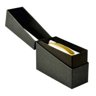 Eine schwarze rechteckige Kartonschachtel von Engravy ist geöffnet und gibt den Blick auf ein glänzendes goldenes Armband frei – ein exquisites personalisiertes Schmuckstück. Der teilweise abgetrennte Deckel ist schräg geneigt, was dieser eleganten Geschenkbox noch mehr Faszination verleiht.