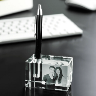 Der Engravy 2D-Stiftehalter mit Foto-Gravur ist ein eleganter Stiftehalter aus klarem Acryl für den Schreibtisch. Er ist mit einem schwarzen Stift und einem personalisierten Schwarzweißfoto eines lächelnden Paares auf einer dunklen Oberfläche mit einer weißen Tastatur versehen. Für eine zusätzliche persönliche Note können Sie ihn mit einer individuellen Gravur personalisieren.