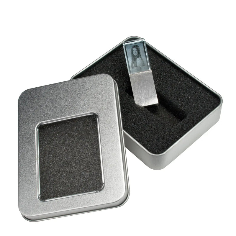 Ein 2D-USB-Stick mit Foto-Gravur von Engravy ist teilweise in eine rechteckige, mit Schaumstoff ausgekleidete Metallbox eingeschoben, deren Deckel links zur Seite gelegt ist.