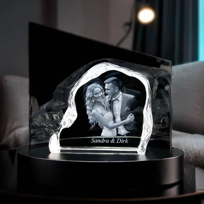 Engravys 3D-Glasgravur – The Rock ist ein atemberaubendes Andenken aus Kristallglas mit einer 3D-Gravur eines lächelnden Paares und der eleganten Inschrift „Sandra & Dirk“ darunter. Dieses Stück mit Premium-Design ruht kunstvoll auf einem schwarzen runden Sockel.