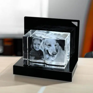 Das Engravy 3D-Glas-Foto Querformat – Dein Moment für die Ewigkeit zeigt eine aufwendige 3D-Gravur eines Kindes und eines Hundes auf einem LED-Leuchtsockel. Auf einem hellen Holztisch mit sanft verschwommenem Hintergrund präsentiert, strahlt es eine bezaubernde Präsenz aus.