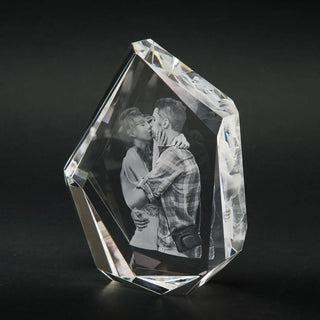 Engravys 3D-Glasgravur – Der Diamant, ein eleganter Kristallglas-Fotoblock im Premium-Format, zeigt ein graviertes, sich umarmendes und küssendes Paar. Vor einem schlichten dunklen Hintergrund hebt es die komplizierten Schliff- und Reflexionseigenschaften des Kristalls hervor.