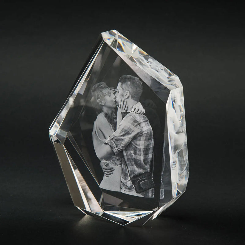 Engravys 3D-Glasgravur – Der Diamant, ein eleganter Kristallglas-Fotoblock im Premium-Format, zeigt ein graviertes, sich umarmendes und küssendes Paar. Vor einem schlichten dunklen Hintergrund hebt es die komplizierten Schliff- und Reflexionseigenschaften des Kristalls hervor.