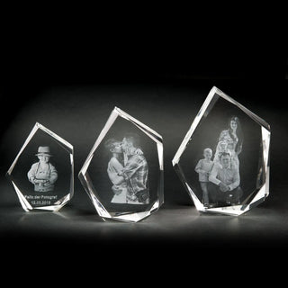 Drei atemberaubende Andenken aus Engravy 3D-Glasgravur-Kristall schimmern auf dunklem Hintergrund. Jedes im eleganten Premium-Format zeigt ein graviertes Foto: links eine Person mit Hut, in der Mitte zwei sich küssende und rechts eine Vierergruppe. Ihre geometrischen Formen haben polierte Kanten.