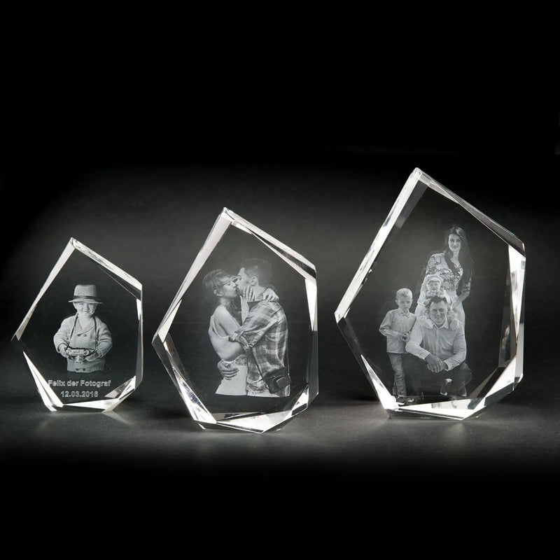 Drei atemberaubende Andenken aus Engravy 3D-Glasgravur-Kristall schimmern auf dunklem Hintergrund. Jedes im eleganten Premium-Format zeigt ein graviertes Foto: links eine Person mit Hut, in der Mitte zwei sich küssende und rechts eine Vierergruppe. Ihre geometrischen Formen haben polierte Kanten.
