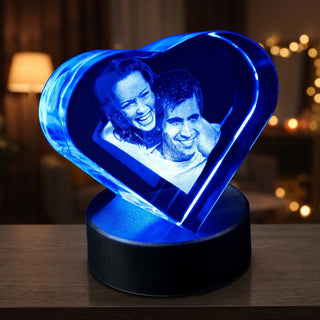 3D-Glasherz mit Fotogravur eines Paares, blau beleuchtet auf dem runden Leuchtsockel
