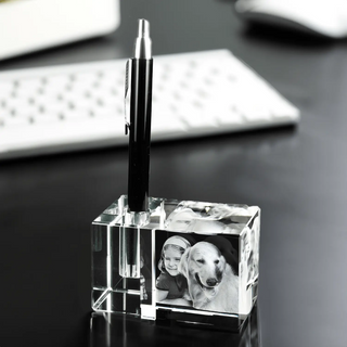Ein Engravy 3D-Stiftehalter mit Foto-Gravur verleiht dem Schreibtisch eine persönliche Note, da er einen schwarzen Stift hält. Daneben verstärken Schwarzweißfotos von einem Kind und einem Hund den Charme, während die schwache Silhouette einer Tastatur diese gemütliche Arbeitsplatzumgebung vervollständigt.