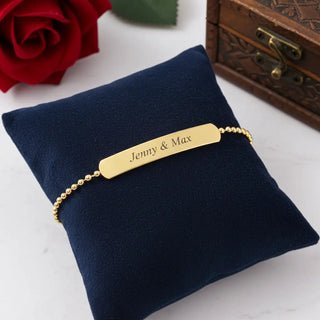 Personalisiertes Gold-Armband mit Namensgravur Jenny & Max auf blauem Samt - romantisches Paar-Geschenk
