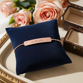 Elegantes Rosegold-Armband mit Datumsgravur auf blauem Samt-Kissen - personalisiertes Geschenk für besondere Momente
