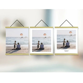 Drei Clipwood Wandbild Quadratisch-Rahmen von Engravy zeigen ruhige Strandszenen mit zwei Personen, die im Sand sitzen und auf das Meer blicken, und einem in der Ferne vorbeiziehenden Parasail. An dünnen Schnüren aufgehängt, verleihen diese Rahmen einen Hauch zeitgenössischen Stils.
