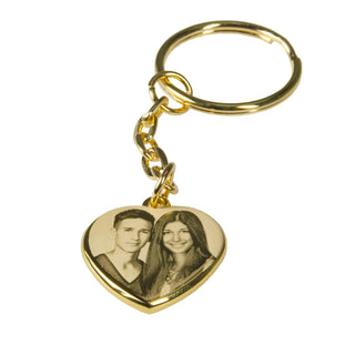 Die personalisierbare Halskette mit Gravur Engravy ist in verschiedenen Formen und Farben erhältlich und verfügt über ein herzförmiges Golddesign mit einem eingravierten Foto eines lächelnden Paares. An einer einfachen Goldkette und einem Ring befestigt, ist sie perfekt, um Ihren Alltagsgegenständen sentimentalen Charme zu verleihen.
