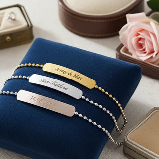 Drei personalisierte Armbänder mit Gravur in Silber, Gold und Rosegold auf blauem Samt - elegante Geschenkidee für Paare und Familie
