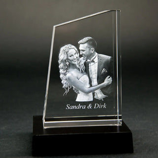 Die Engravy Premium 3D-Glasgravur – The Tower zeigt eine 3D-Gravur eines lächelnden Paares in formeller Kleidung mit „Sandra & Dirk“. Dieses einzigartige Design wird elegant auf einem schwarzen Untergrund dargestellt.