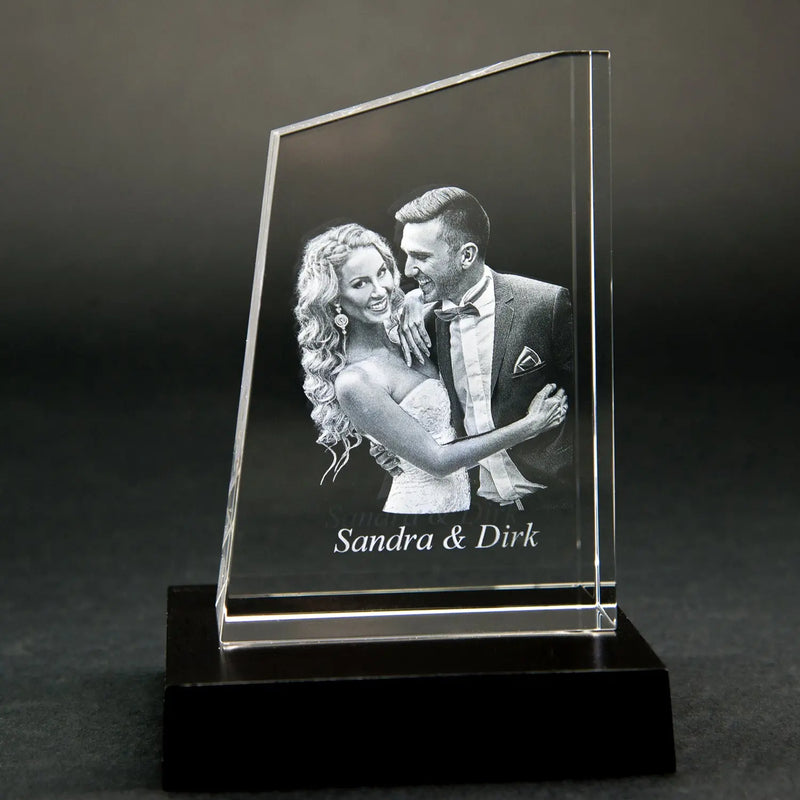 Die Engravy Premium 3D-Glasgravur – The Tower zeigt eine 3D-Gravur eines lächelnden Paares in formeller Kleidung mit „Sandra & Dirk“. Dieses einzigartige Design wird elegant auf einem schwarzen Untergrund dargestellt.