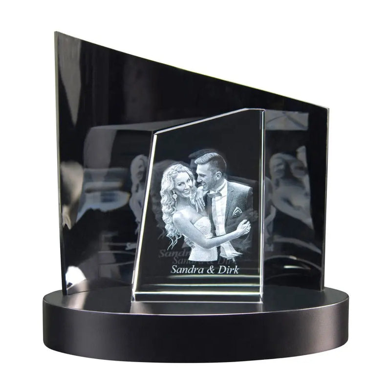 Eine Premium-3D-Glasgravur von Engravy, „The Tower“, zeigt ein lächelndes Paar, das auf einem schwarzen runden Sockel mit einem eckigen schwarzen Hintergrund tanzt. Die Namen „Sandra & Dirk“ sind darunter eingraviert und werden durch exquisites Design für besondere Momente zum Leben erweckt.