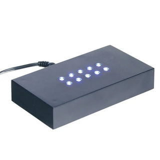 Die Engravy Sockelscheibe selbstehend Hochformat ist ein rechteckiges schwarzes Gerät mit einem Gitter aus kleinen blauen LED-Leuchten auf der Oberseite, ähnlich einem modernen Leuchtsockel, mit einem schwarzen Kabel an der Seite, vor einem schlichten weißen Hintergrund.