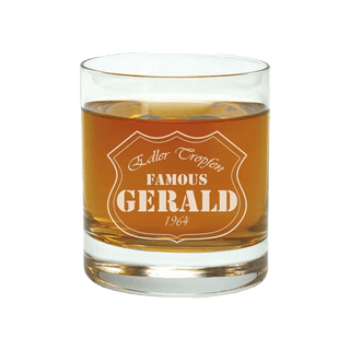 Ein personalisiertes 400 ml Whiskyglas von Engravy, gefüllt mit bernsteinfarbener Flüssigkeit und mit der Aufschrift „Edler Tropfen FAMOUS GERALD 1964“ macht es zu einem idealen Geschenk.